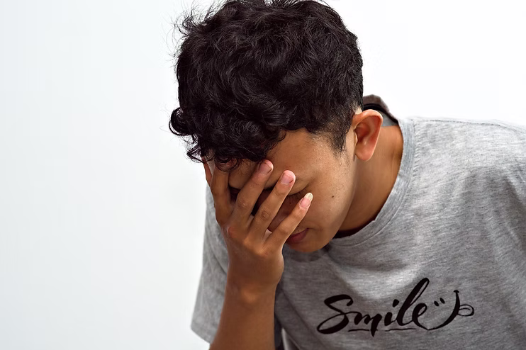 Jeune homme tenant sa tête dans sa main, évoquant le doute