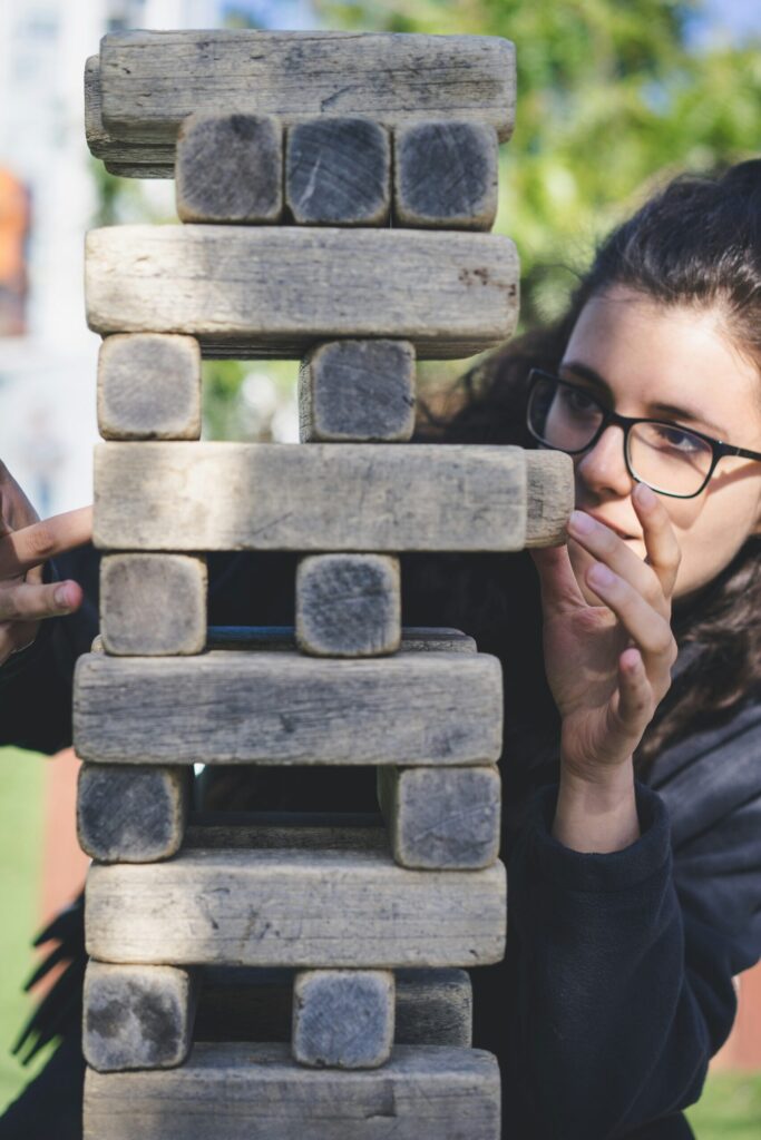 Jeune femme jouant au Jenga, symbole des schémas répétitifs et des équilibres fragiles qui se rejouent