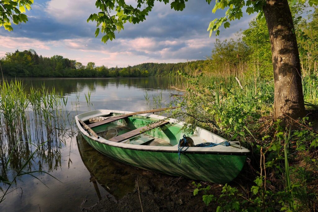 Bateau vert au bord d’un lac paisible, symbole de libération intérieure et d’alignement.
