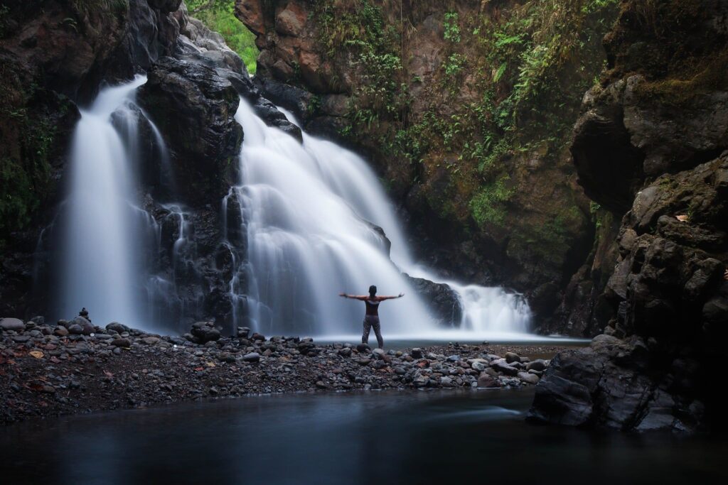 Personne face à une cascade, les bras ouverts, évoquant la force, la liberté et la confiance retrouvée.