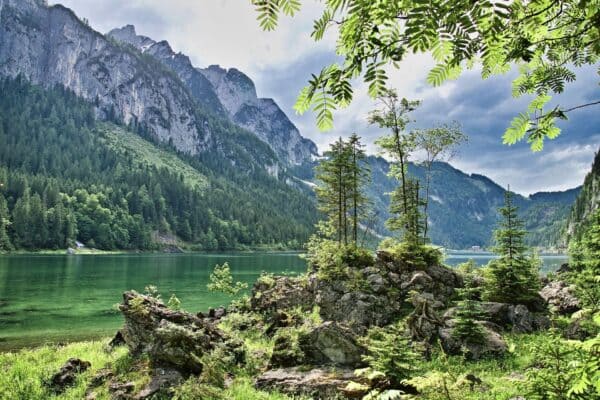 Vue sur un lac vert entouré de montagnes et de forêt, évoquant la paix et l’alignement.